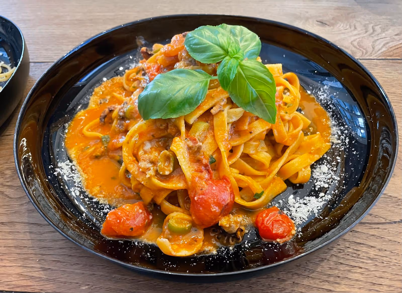 Pasta mit Garnelen und Basilikum auf schwarzem Teller.