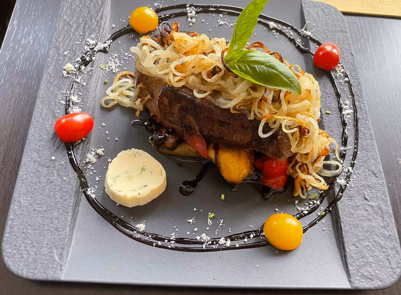 Hauptgericht mit Fleisch, Gemüse und Sauce, dekorativ angerichtet.