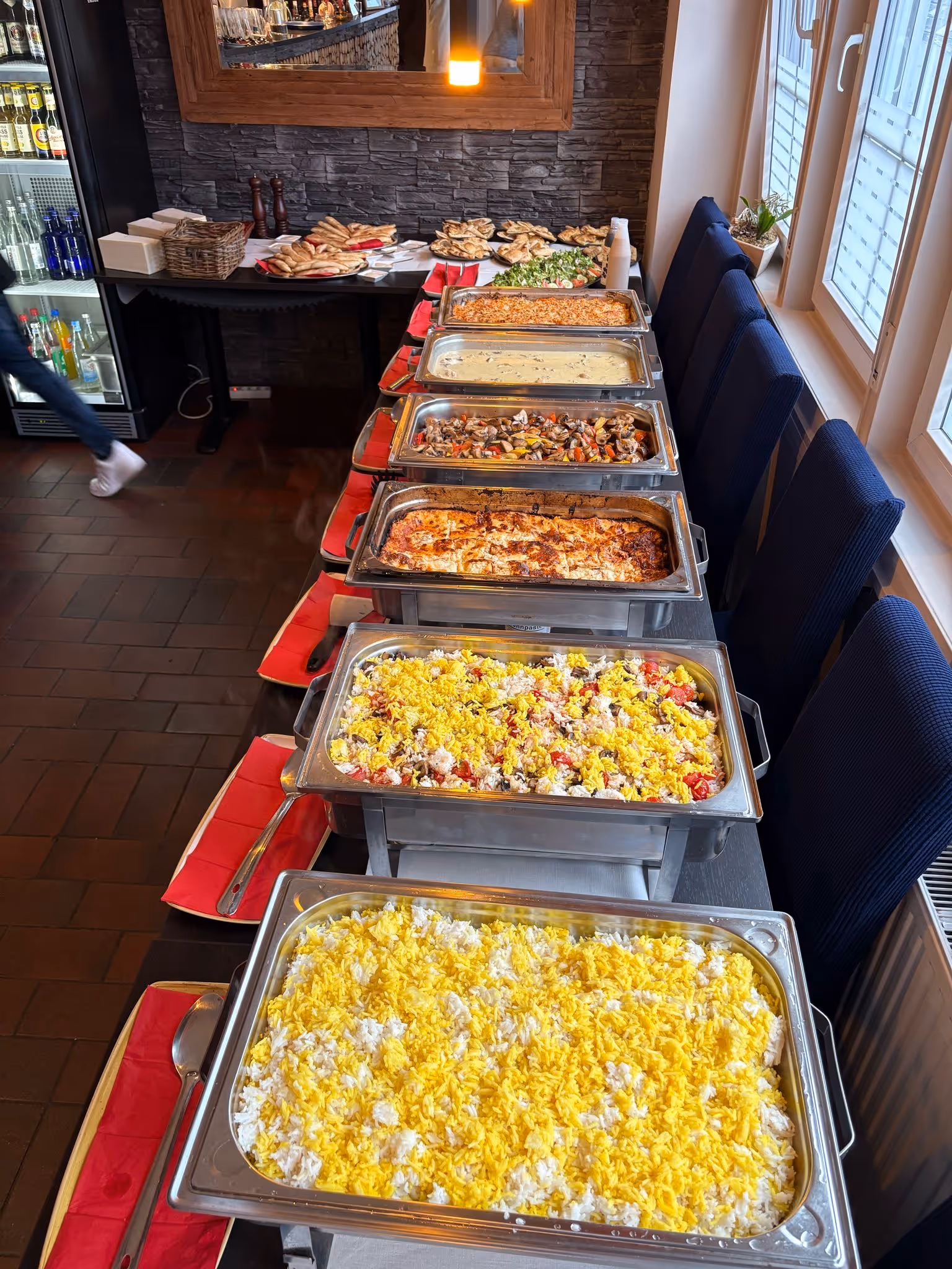 Langes Buffet mit verschiedenen warmen Speisen in Schalen.