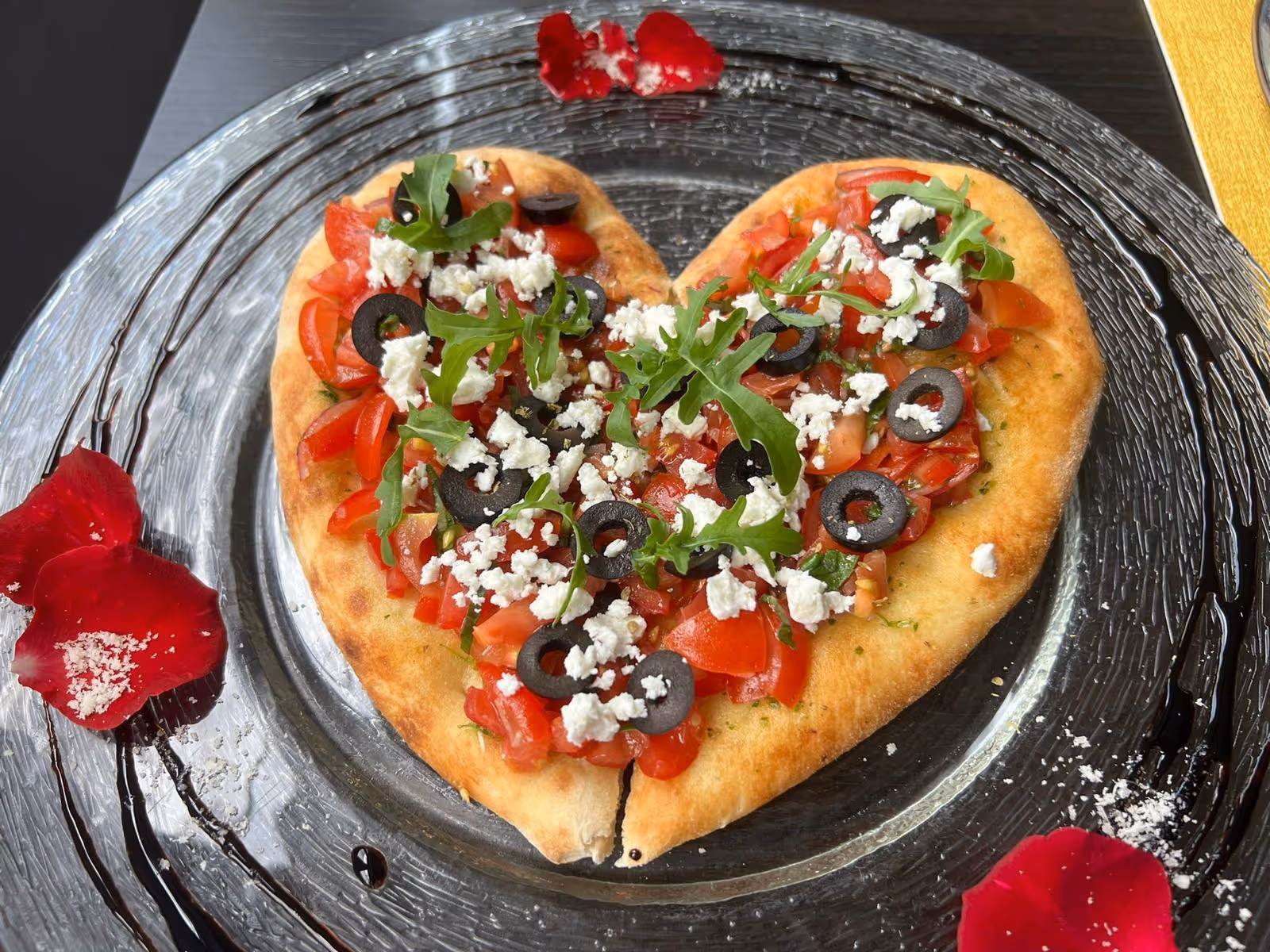 Herzförmige Pizza mit Tomaten, Mozzarella und Basilikum.